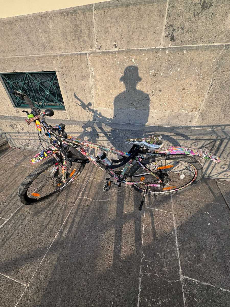 Silhouette de Gwen et son vélo, ombre sur mur de pierre au soleil
